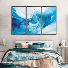 two paintings on the wall above a bed in a room with a blue comforter