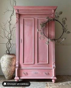 a pink armoire next to a potted plant