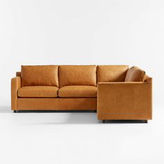 a tan leather sectional sofa sitting on top of a white floor