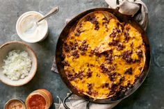 a casserole with meat and cheese in a pan next to other dishes on a table