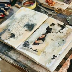 an open book sitting on top of a wooden table next to scissors and other art supplies