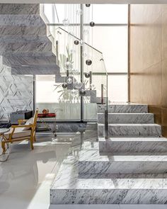 an elegant staircase with marble steps leading up to the second floor and glass railings