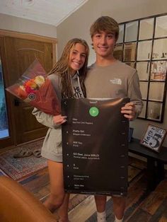 a young man and woman standing next to each other holding up a sign that says the menu