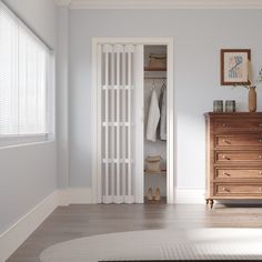 an empty room with white walls and wooden furniture, including a chest of drawers in the foreground