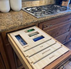 a kitchen counter top with drawers that are open and labeled for different types of cooking utensils