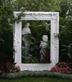 an ornate white mirror in the middle of a garden