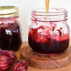 a jar filled with red liquid sitting on top of a wooden cutting board next to another jar