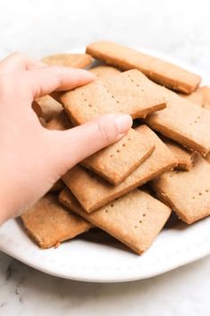 a hand reaching for crackers on a white plate