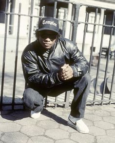 a man sitting on the ground in front of a fence