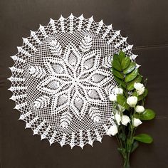 a white crocheted doily next to a bouquet of flowers