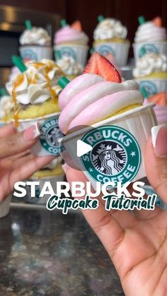 starbucks cupcakes with pink frosting and strawberries in the middle are being held up by someone's hand