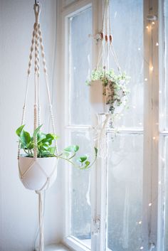 two hanging planters with plants in them next to a window