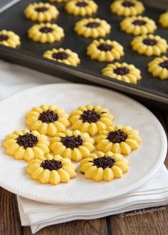 some cookies are sitting on a white plate near a pan with other cookies in it