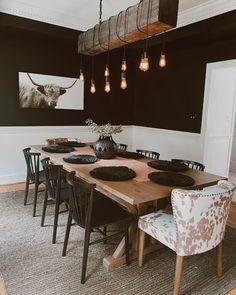 a dining room table and chairs with lights hanging from the ceiling