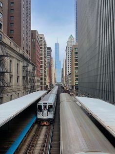 a train traveling down tracks next to tall buildings in a city with high rise buildings