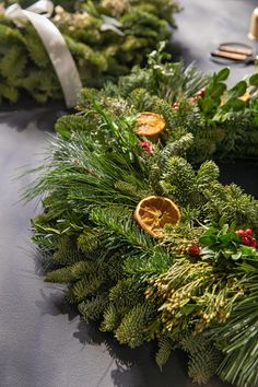 wreaths with orange slices and greenery are on the table, ready to be used as decorations