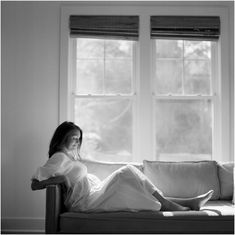 a woman sitting on top of a couch next to a window