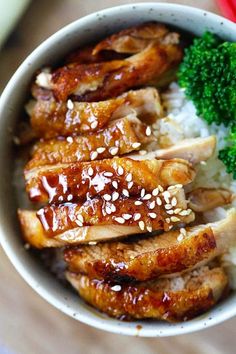 a bowl filled with chicken, rice and broccoli on top of a wooden table