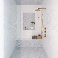 a bathroom with white and blue tiles on the walls, shower head, and shelf