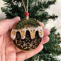 a hand holding a christmas ornament in front of a tree