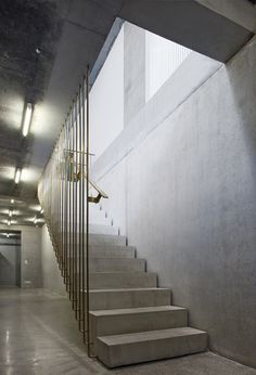 the stairs are made of concrete and lead up to an open space with light coming in