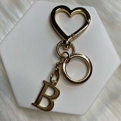 a heart shaped keychain with the letter b on it sitting on a white plate