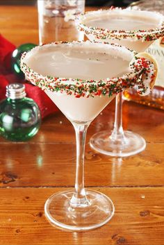 two martinis with sprinkles sit on a table next to christmas decorations