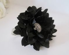 a black flower with some white roses in the background and a ring on it's side