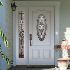 a white front door with stained glass and potted plant in the foreground on a sunny day