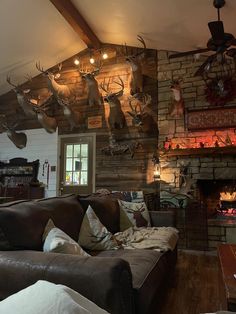 a living room filled with furniture and deer heads mounted to the wall above it's fireplace