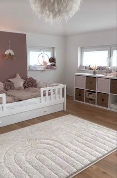 a white bed sitting on top of a wooden floor next to a dresser and window