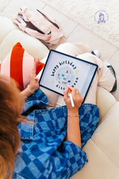 a woman is sitting on the floor with her ipad and writing happy birthday wishes to someone