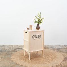 a small wooden cabinet with a plant on top and the word gardig written on it