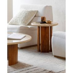 a white couch sitting next to a wooden table on top of a carpeted floor