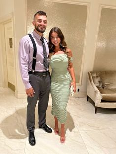 a man and woman standing next to each other in front of a living room with couches