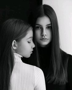 two young women standing next to each other with their heads close together in black and white