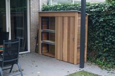 an outdoor table and chairs in front of a wooden storage unit with sliding doors on the side