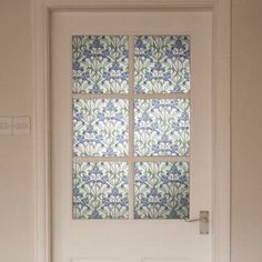 a white door with blue and green flowers on the glass paneled window above it