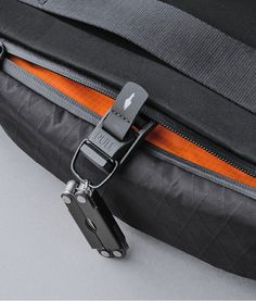 an orange and black strap is attached to the side of a bag with a metal buckle