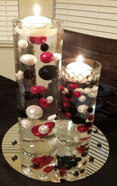 two tall vases filled with water and red, white and black balls on top of each other