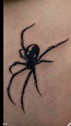 a black spider tattoo on the back of a woman's shoulder