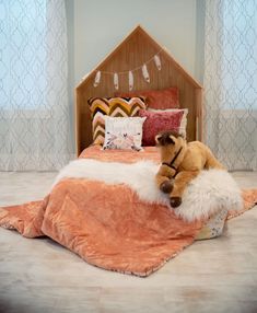 a teddy bear laying on top of a bed in a room with pillows and blankets