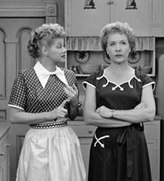 two women standing next to each other in a kitchen