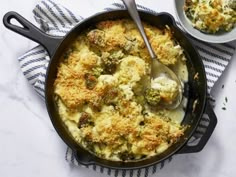 a skillet filled with broccoli and cheese next to a bowl of sauce