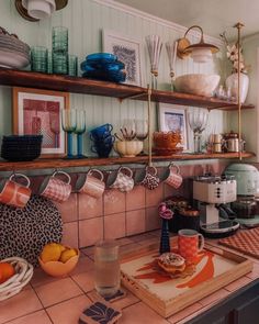 a kitchen counter topped with lots of plates and bowls next to a shelf filled with dishes