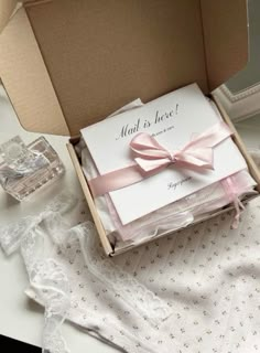 an open box with a pink bow on it sitting on a table next to other items