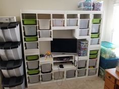 a room with several shelves and bins on the wall, including a computer monitor