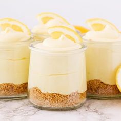 lemon cheesecake in small glass jars with sliced lemons around the edges and on top