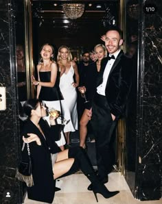 a group of people standing around each other in front of a doorway with black marble walls