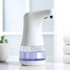 a white and blue blender sitting on top of a counter next to a potted plant